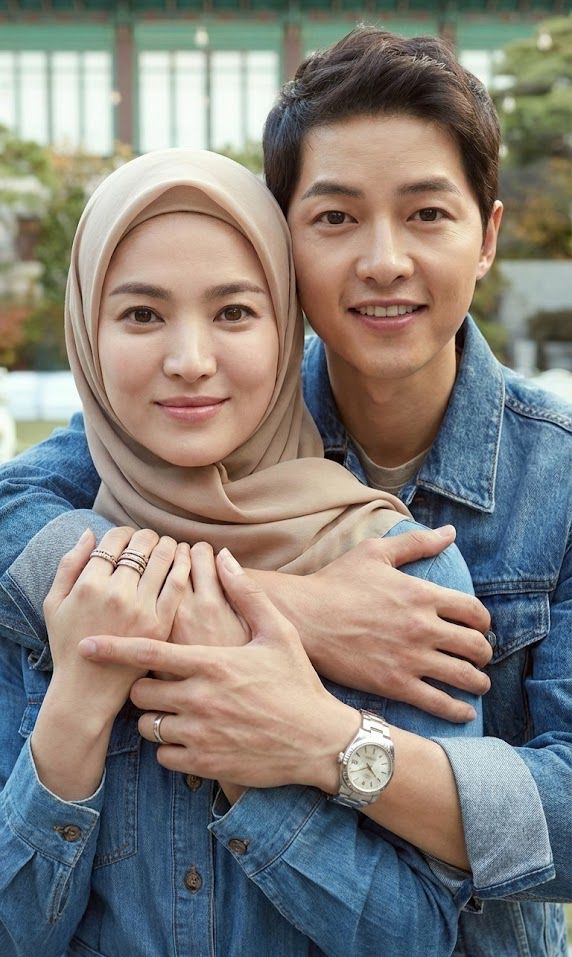 A close-up of a couple embracing, showcasing their hands and wrists adorned with rings and watches. 