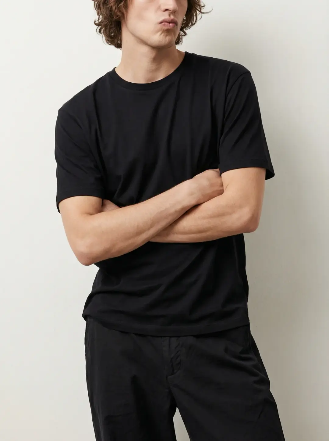 Photograph a male model wearing a nice fit pure black cotton t-shirt with a soft texture. The shirt 