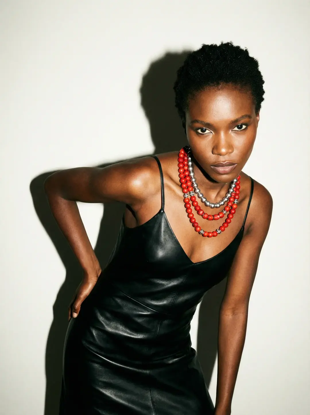 Fashion editorial portrait of a confident Black woman wearing a black leather dress with thin straps